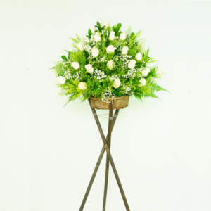 White roses and greeneries arranged in a wooden basket.