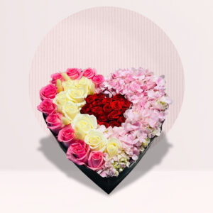 a heart-shaped arrangement of flowers in a black box