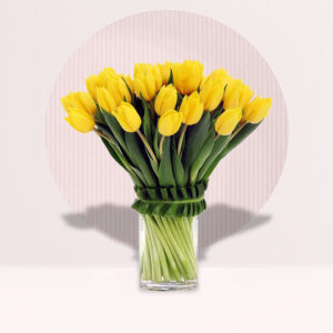 a bouquet of bright yellow tulips arranged in a clear glass vase